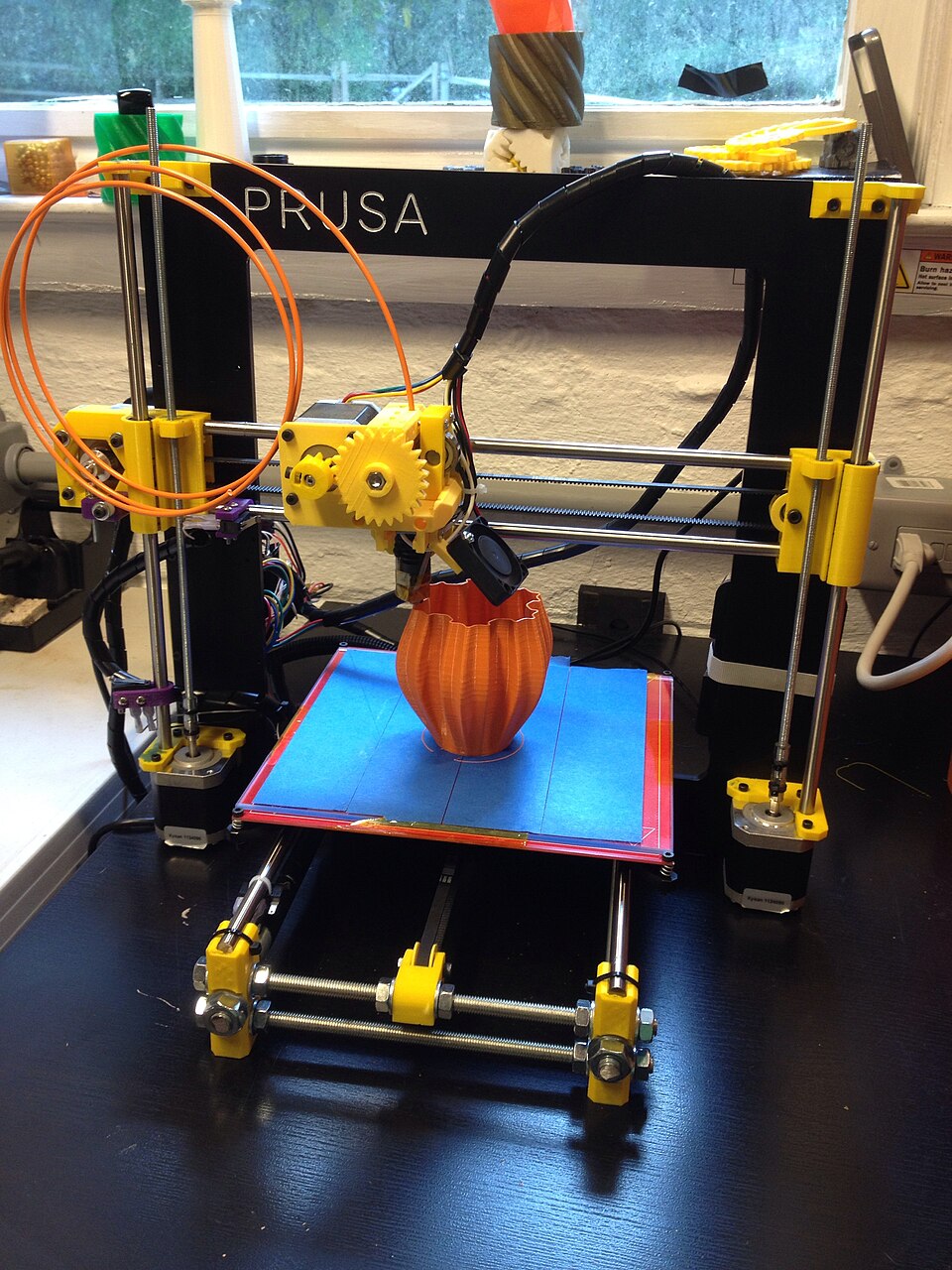 طابعة Prusa i3 من نوع Bed-slinger تطبع مزهرية برتقالية